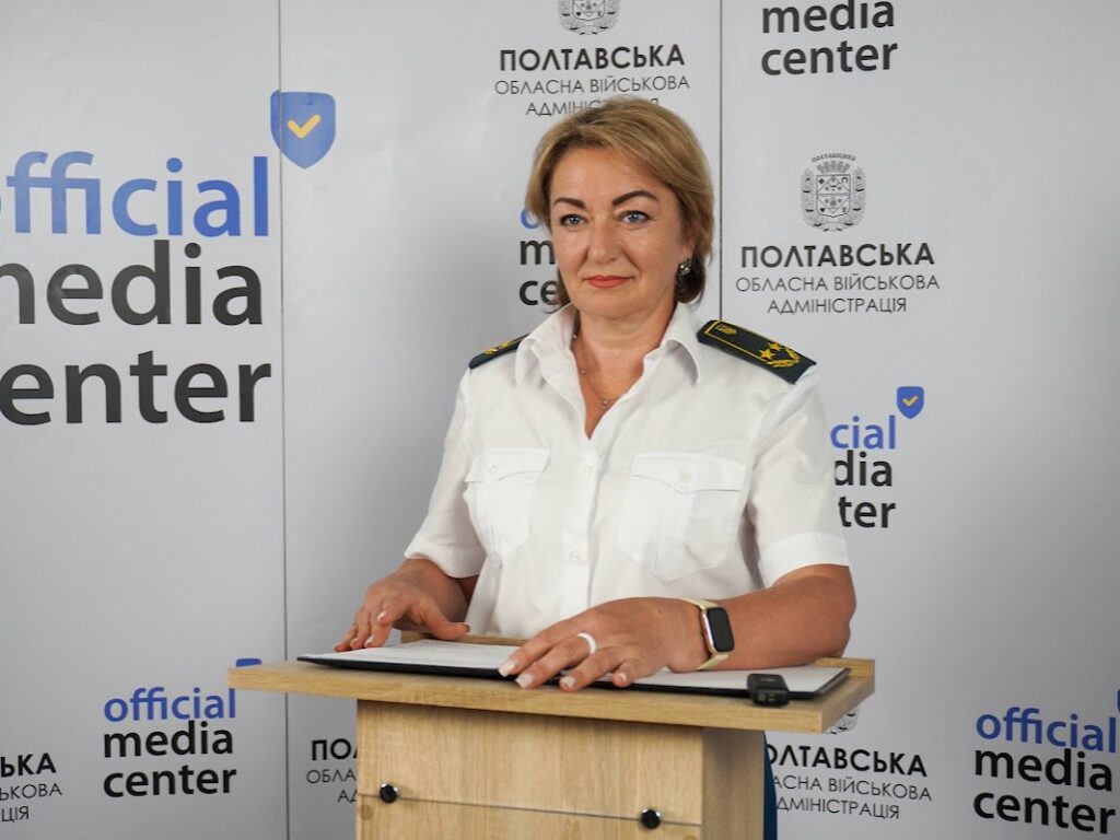 Олена Журбенко у формі митника на фоні баннера "Офіційний медіацентр Полтавщини", за трибуною з документами