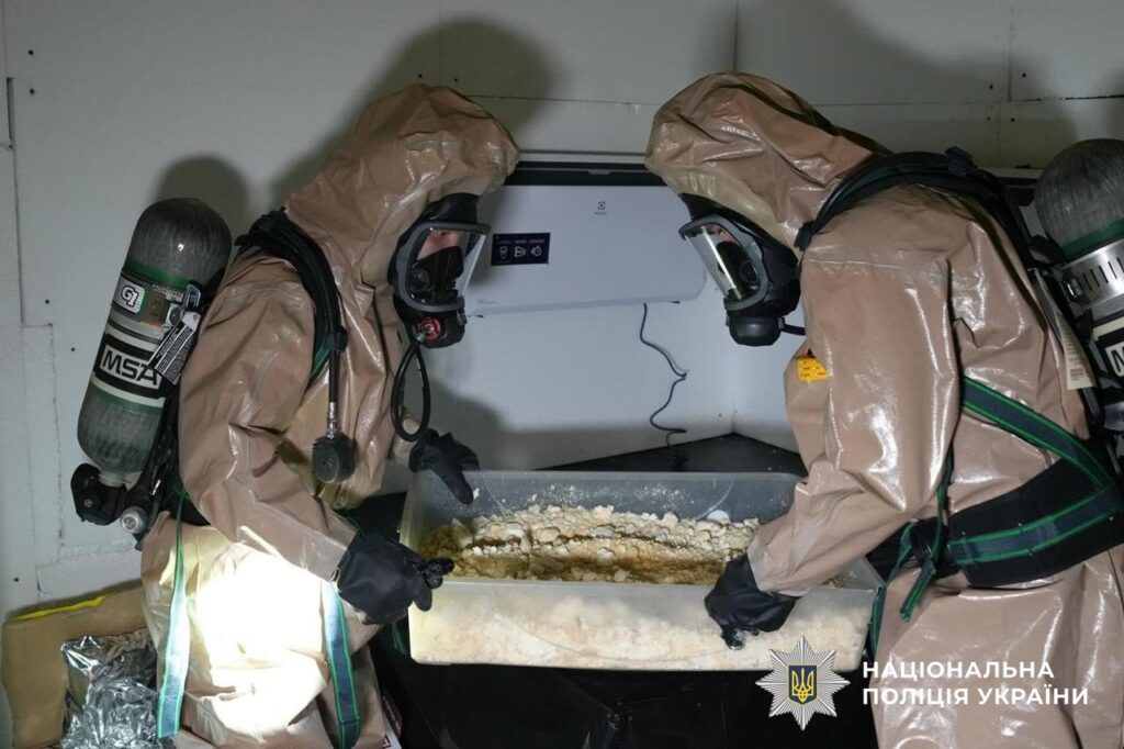 правоохоронці в хімзахисті виносять із приміщення сировину для наркотиків