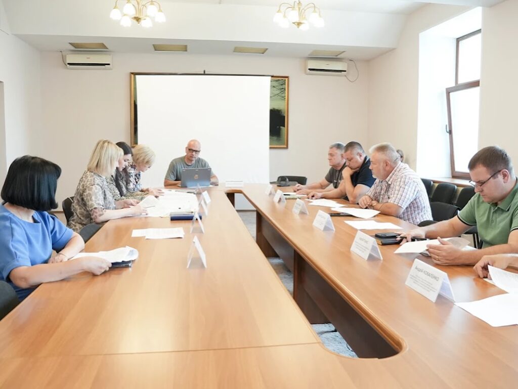Кімната засідань, люди за столом, на столі документи