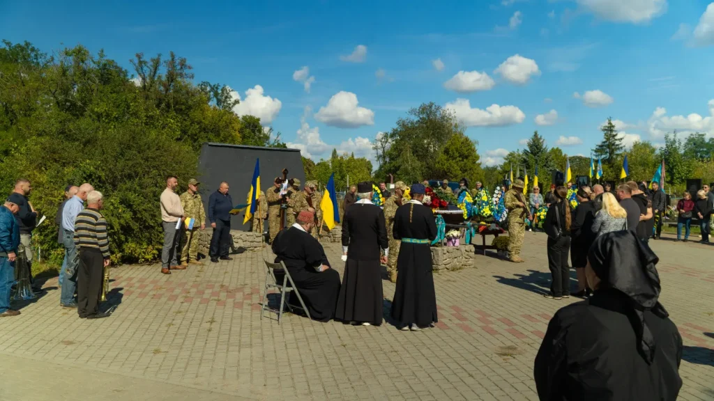 люди стоять на площі навколо труни