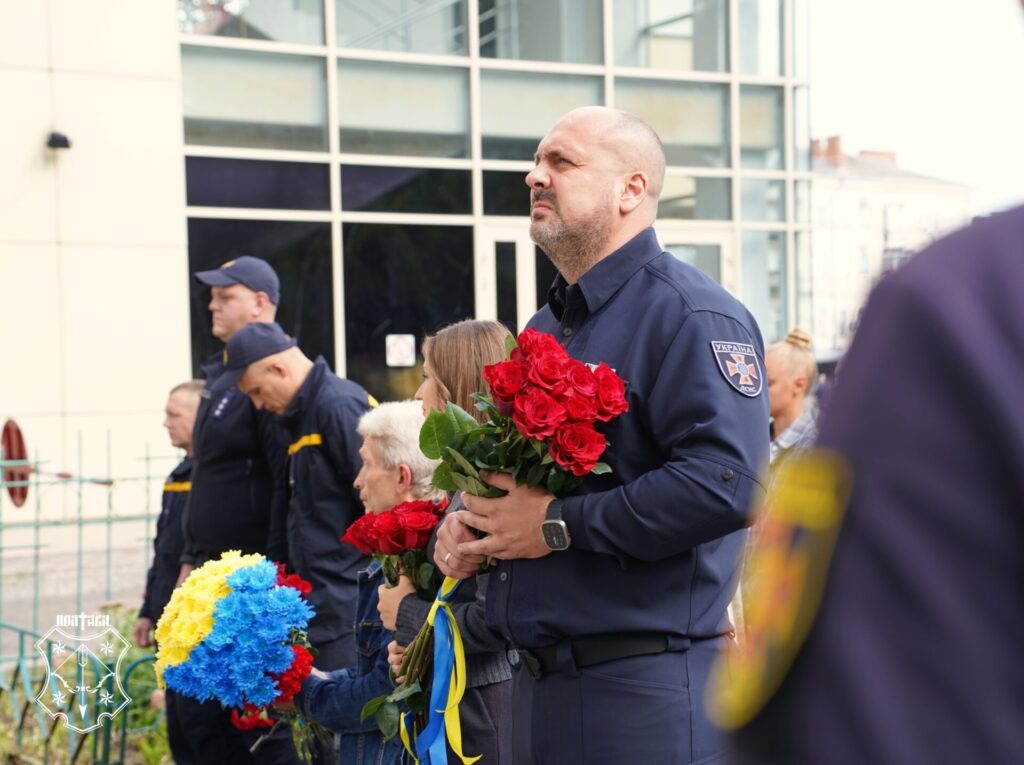начальник гарнізону тримає букет троянд і дивиться вгору