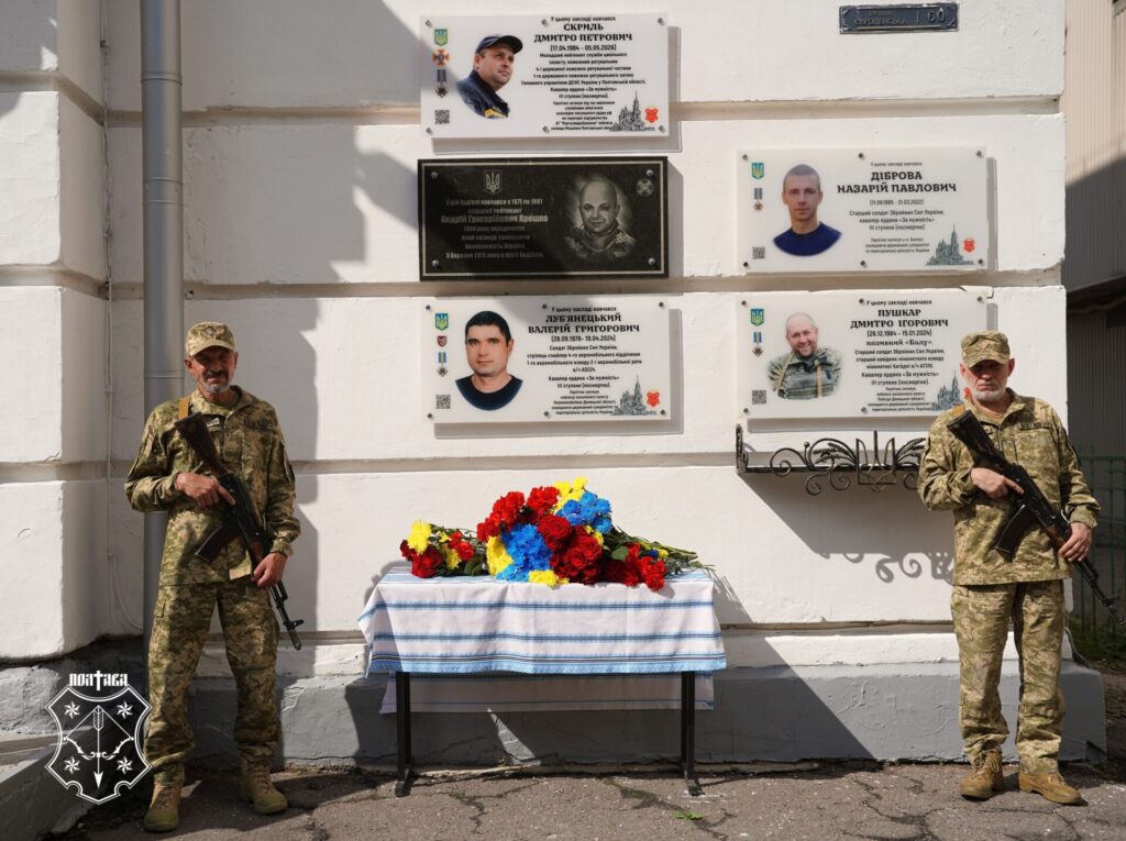 почесна варта біля меморіальних дошок і стола з квітами