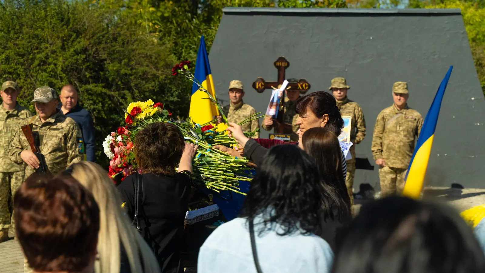 люди кладуть квіти на труну