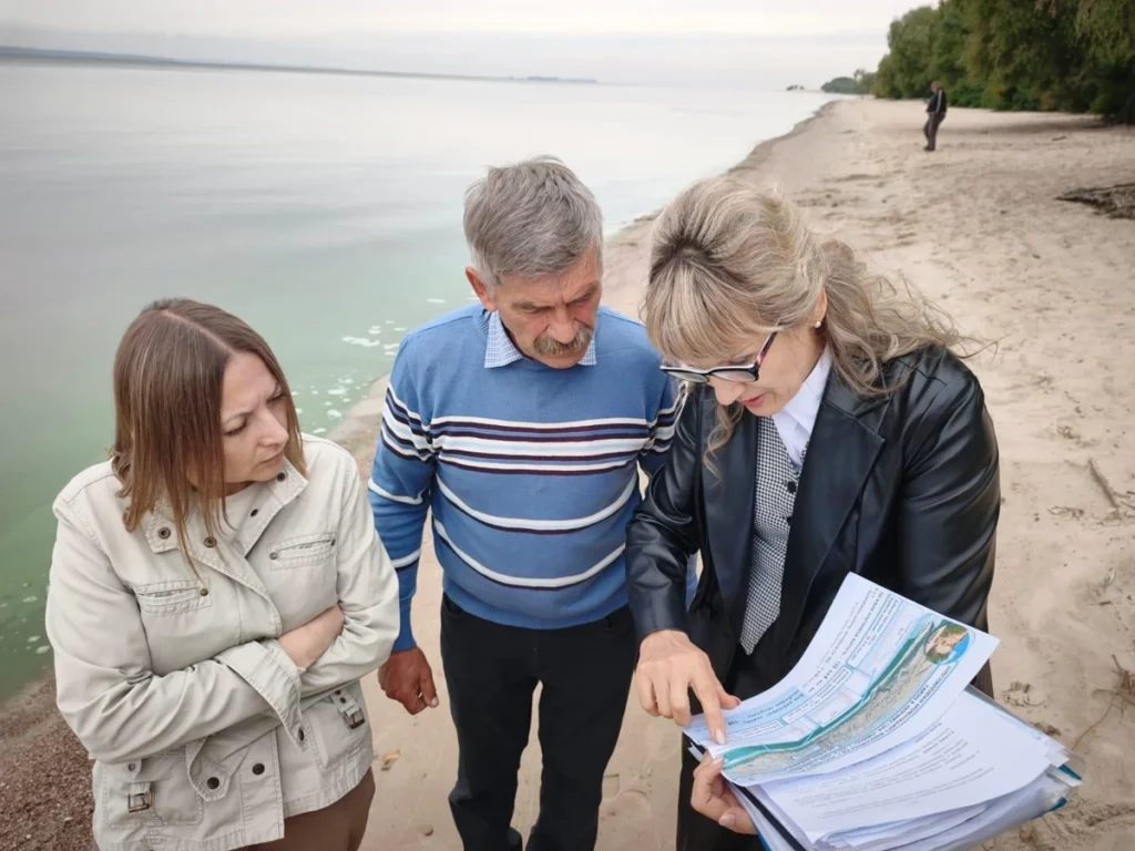люди обговорюють зазначене в документах, стоячи на березі водосховища