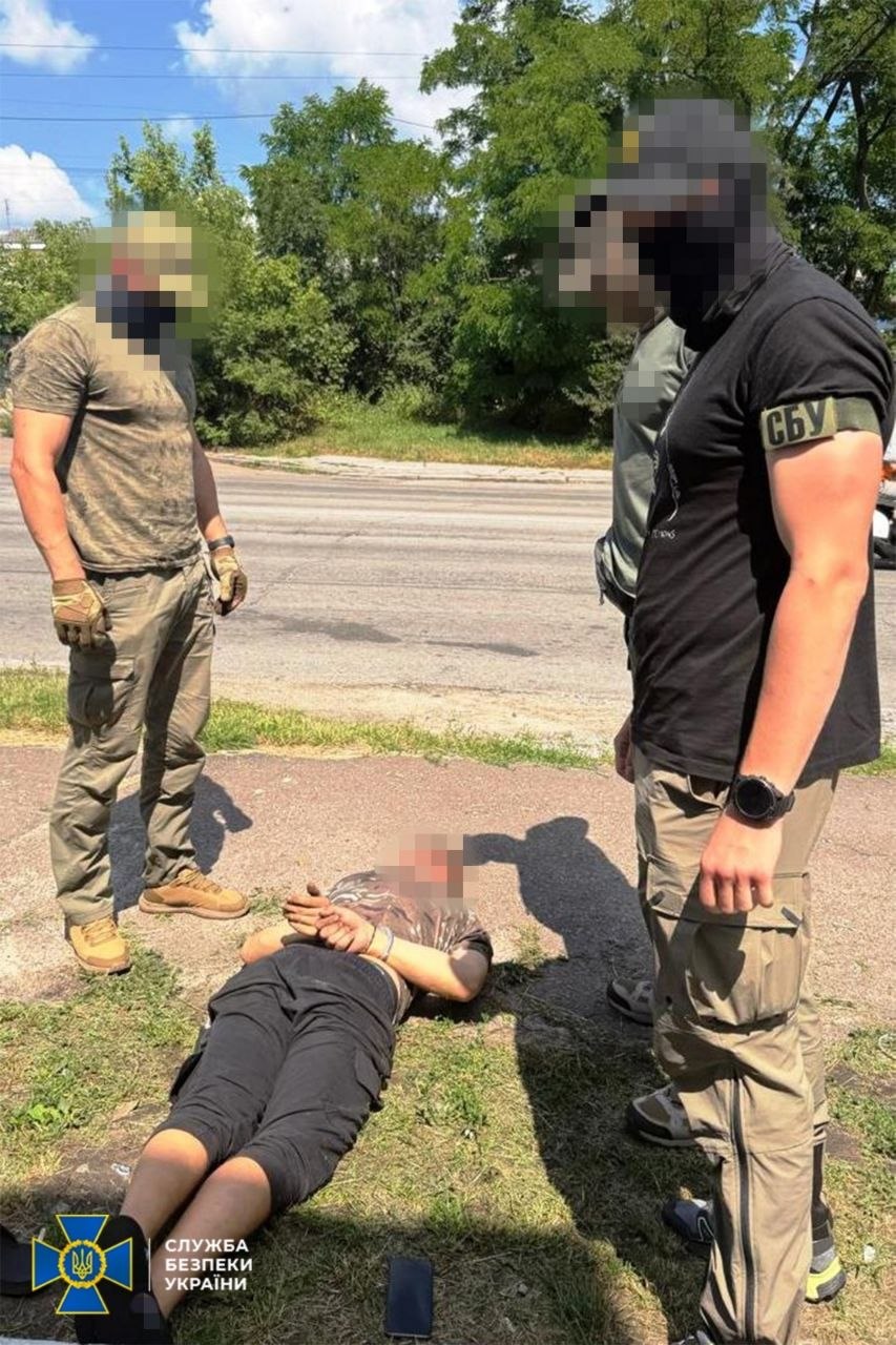 стоять двоє співробітників СБУ лежить людина на землі, з руками, заведеними назад