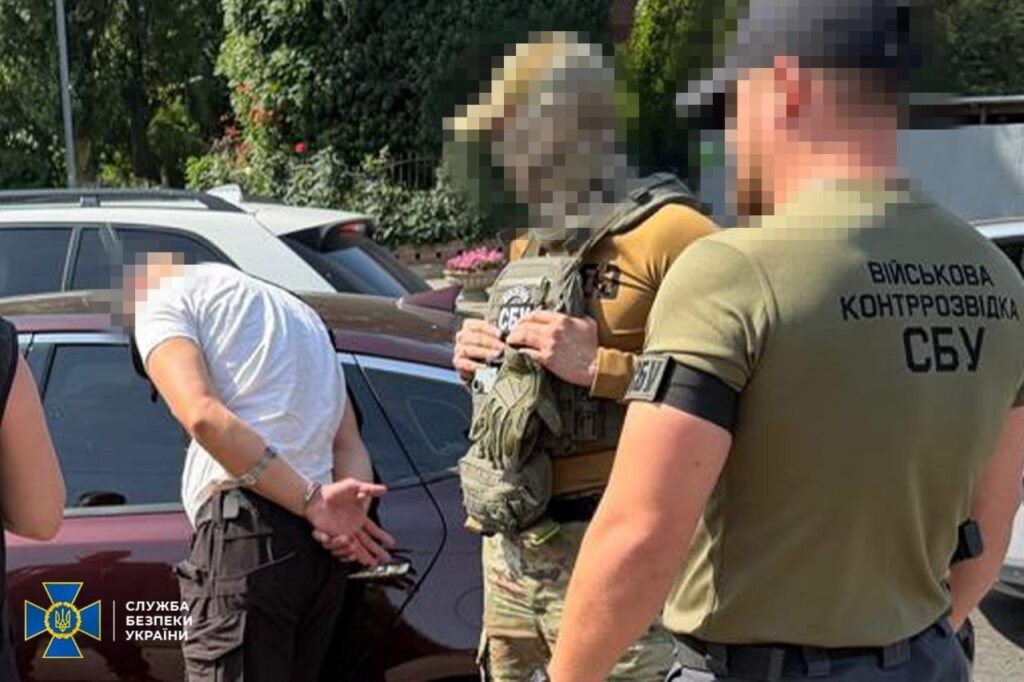 затриманий чоловік біля машини, поруч три правоохоронці