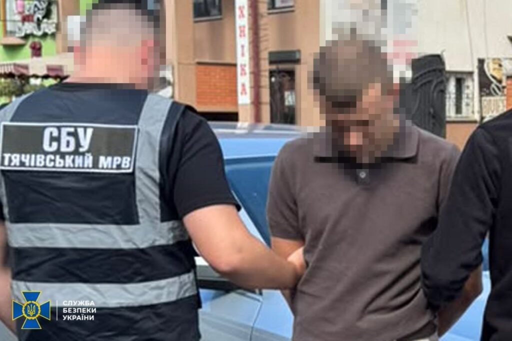 затриманий чоловік біля машини, поруч два правоохоронці