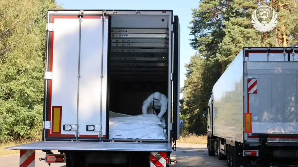 Відкритий кузов вантажівки з тілами загиблих і людина біля них