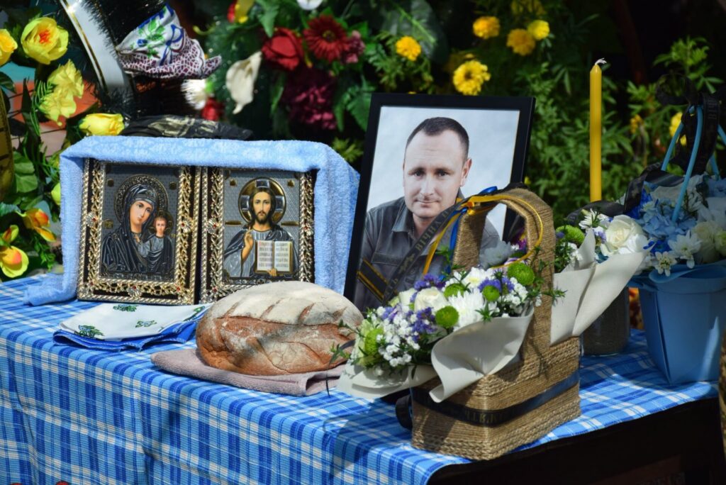 портрет воїна, ікони, свічки, квіти, хліб