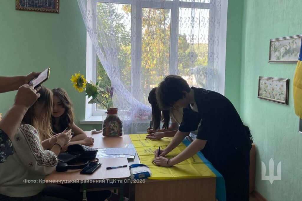 учні підписують прапор, що лежить на столі