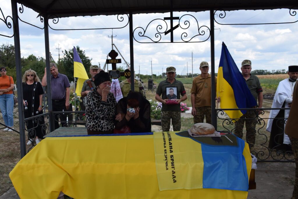 жінка плаче над труною на кладовищі