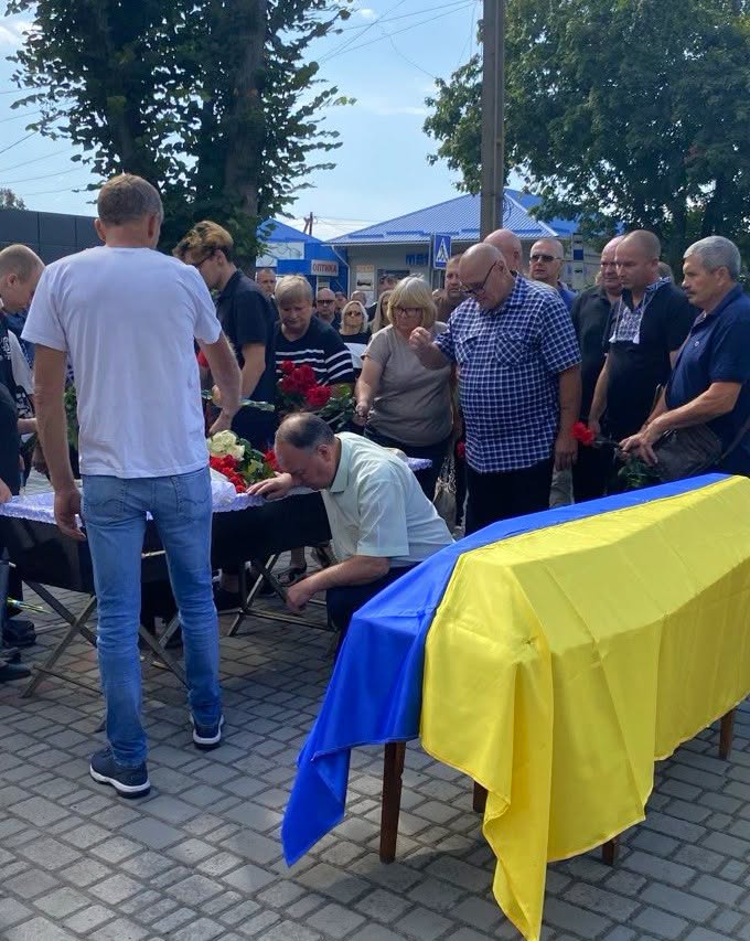 люди біля труни прощаються із загиблим військовиком