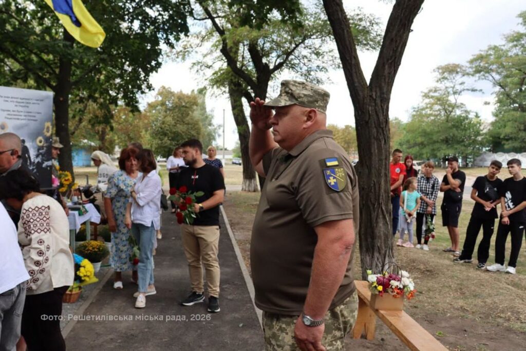 військовикі віддає честь перед портретами полеглих