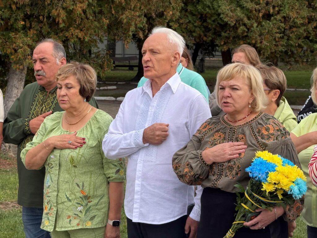 люди стоять на вулиці, тримаючи праву руку біля серця