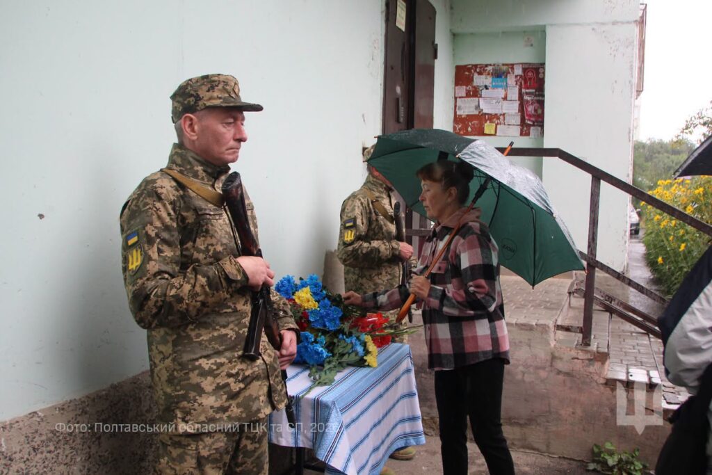 люди кладуть квіти до меморіальної дошки