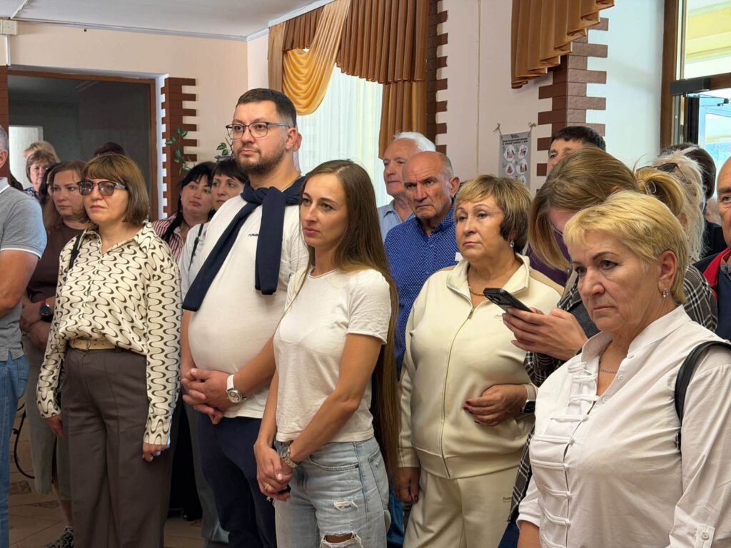 люди стоять у приміщенні біля вікон