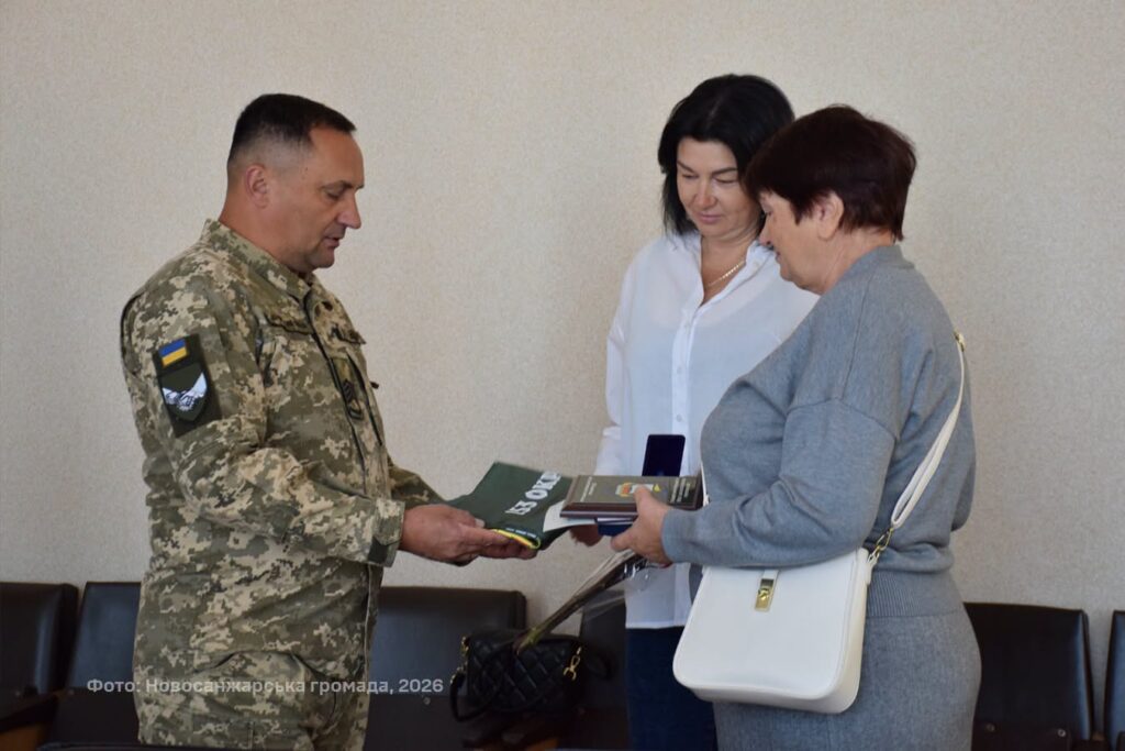 військовик передає нагороду та прапор двом жінкам