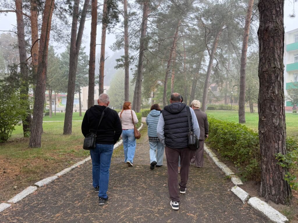 Люди йдуть по гравійній доріжці міцж дерев до будиночків