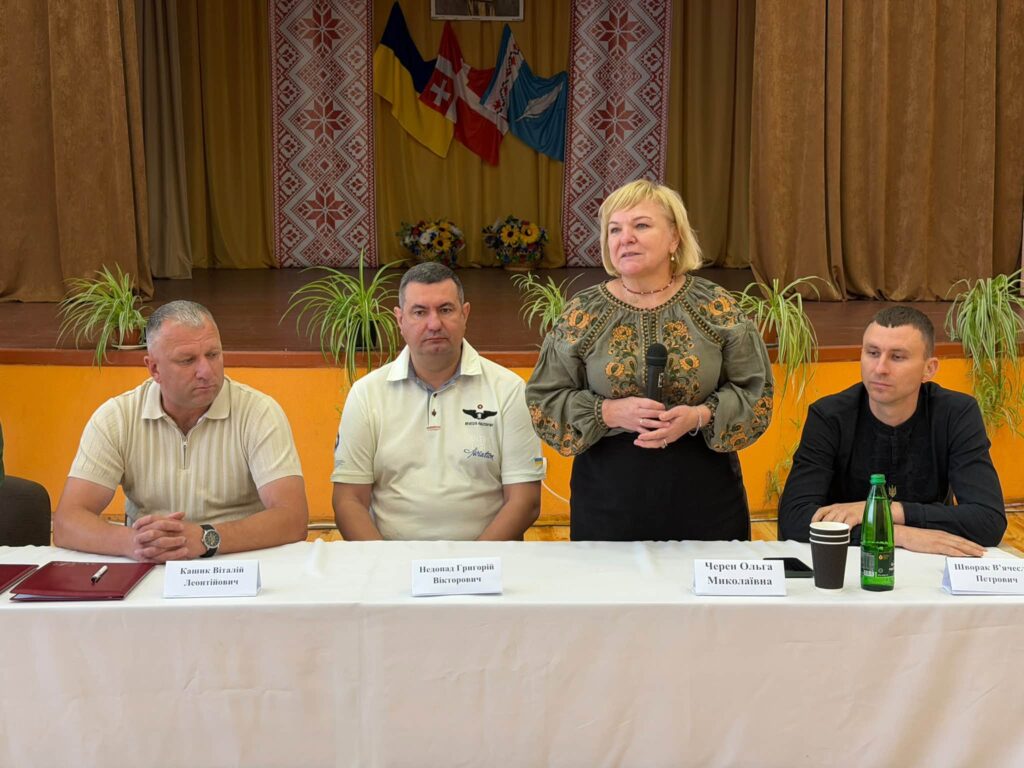 Люди за столом президії, виступає жінка