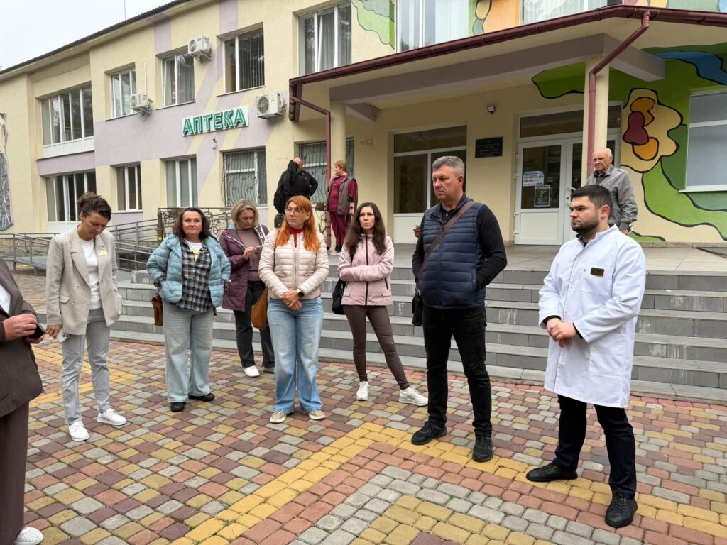 Люди перед двоповерховою будівлею
