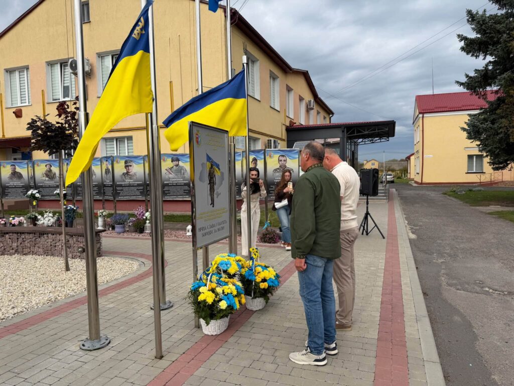 Двоє чоловіків стоять біля портретів на Алеї Героїв