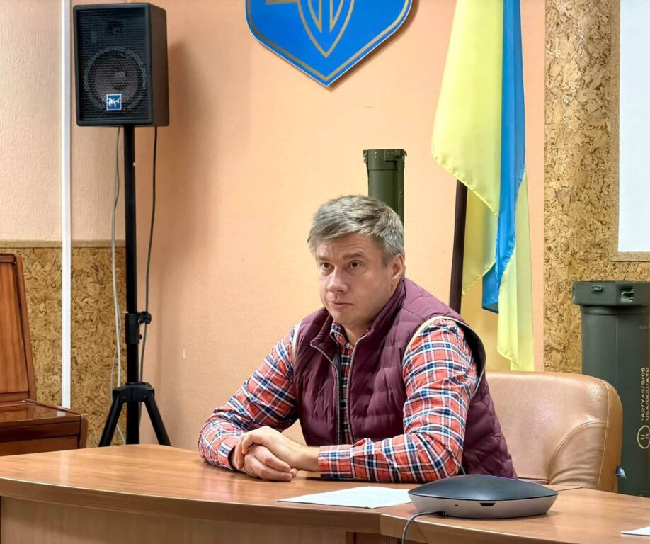 Олександр Біленький за столом, позаду нього прапор України