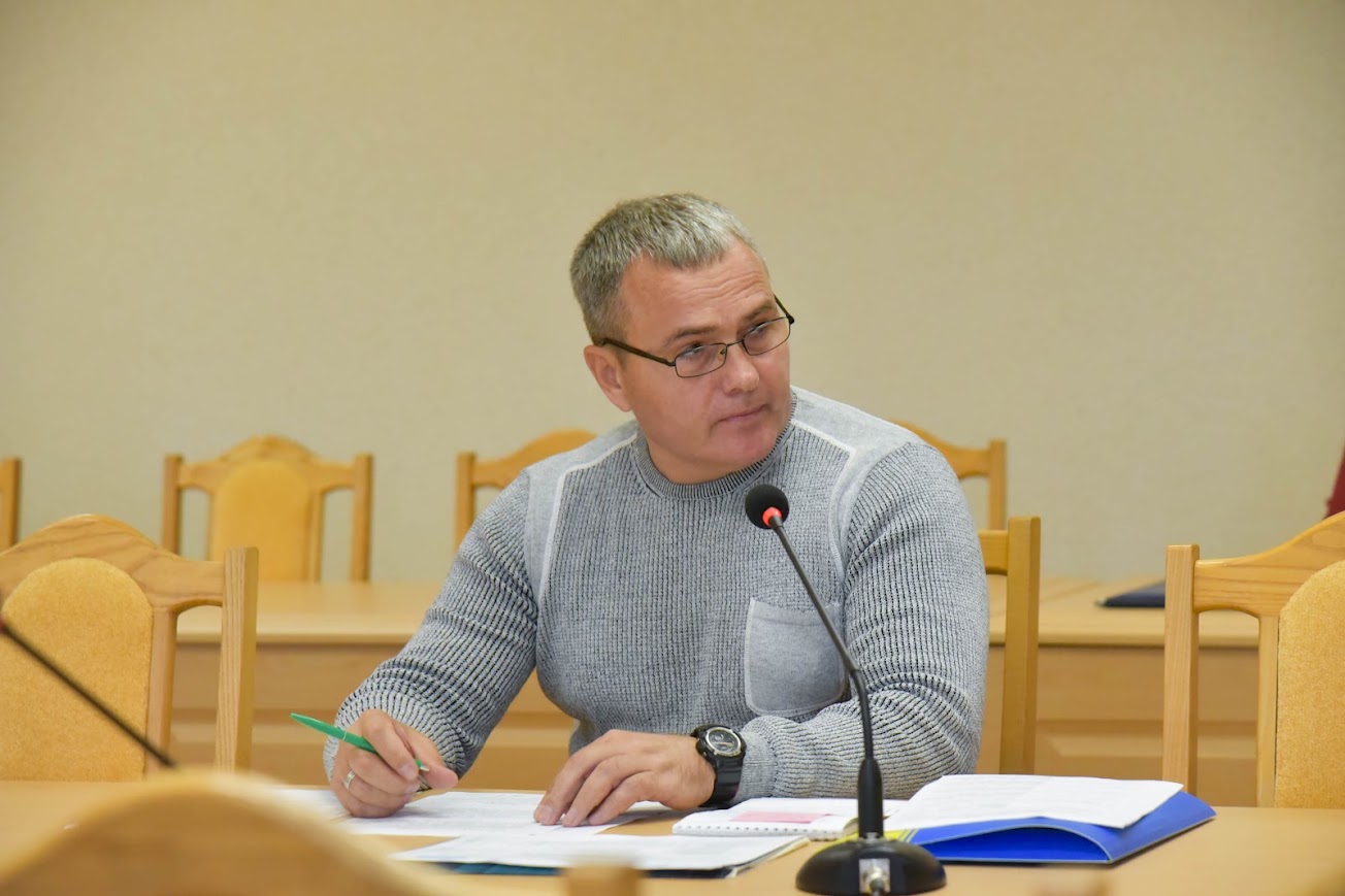 чоловік із документами за столом, перед ним мікрофон