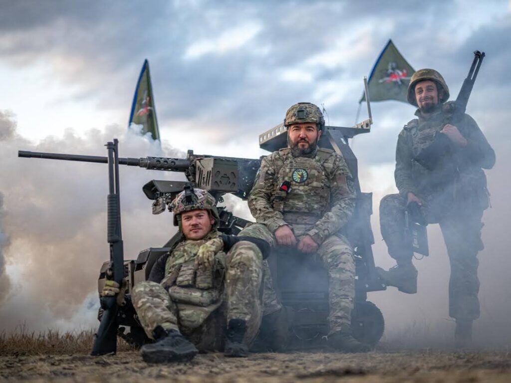 Троє воїнів поряд із озброєнням, навколо дим