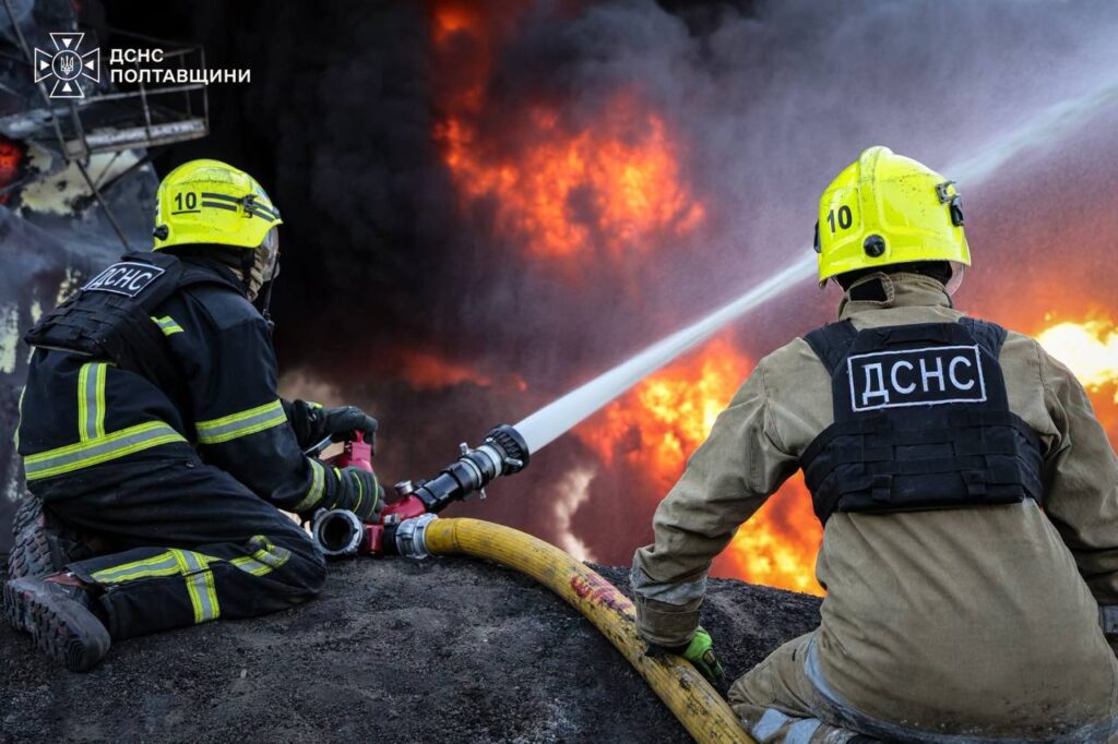 Двоє рятувальників гасять пожежу з брандспойту