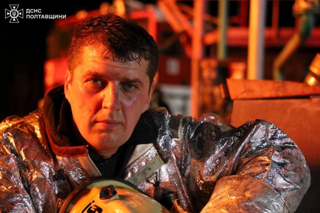 Рятувальник у спецодязі для гасіння пожеж із каскою в руках