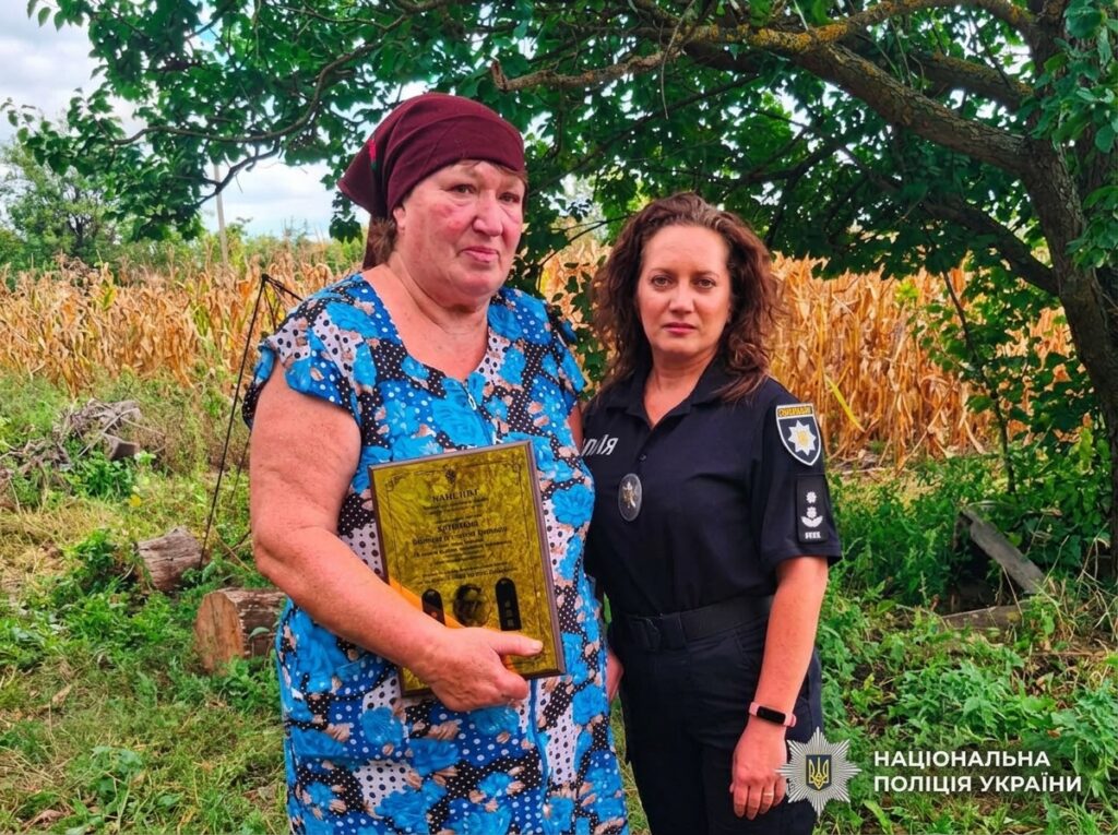 поліцейський передає нагороду родичці зниклого безвісті поліцейського.