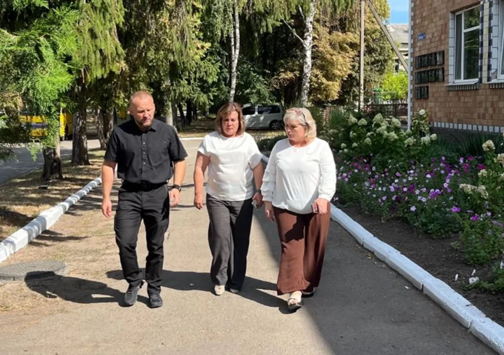 по алейціі біля будівлі йдуть чоловік і дві жінки
