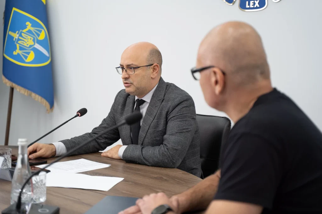 сидить людина за столом та говорить в мікрофон