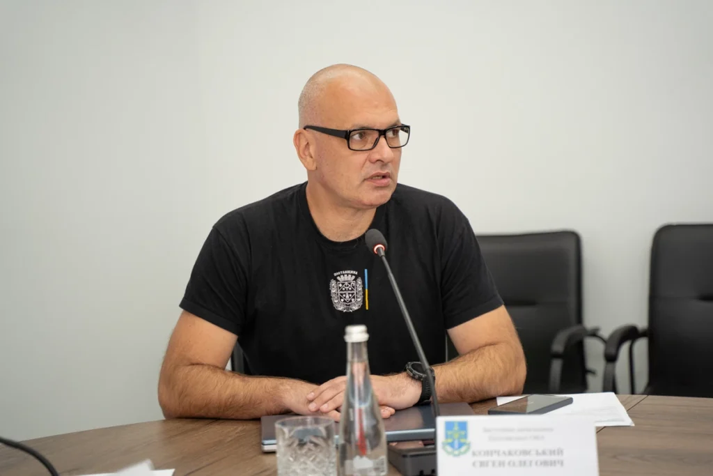 сидить людина за столом та говорить в мікрофон