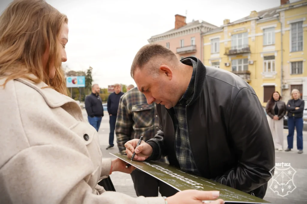 чоловік підписує табличку, яку тримає жінка