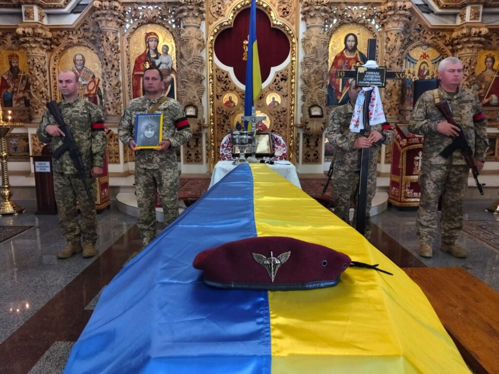 труна, накрита державним прапором, на ній берет штурмовика, біля алтаря воїни траурної варти з портретом, хрестом і зброєю