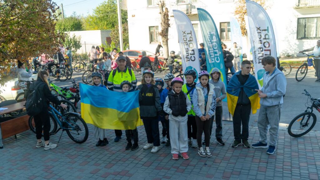 люди з велосипедами біля прапорів організацій, які проводять захід
