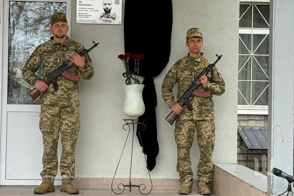 біля закритої чорною тканиною меморіальної дошки стоїть почесна варта з двох військовослужбовців