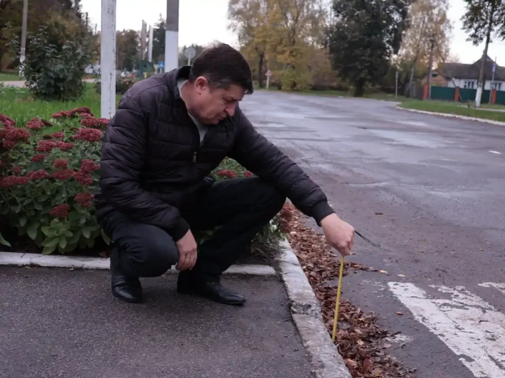 уповноважений вимірює висоту бордюра біля пішохідного переходу