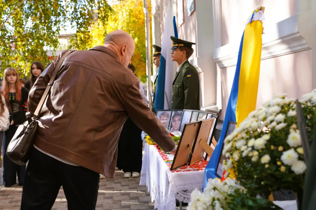 чоловік кладе квіти до портретів полеглих
