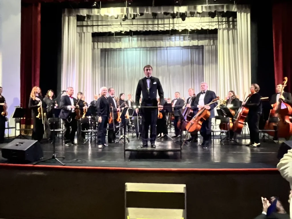 нинішній диригент із оркестром на сцені