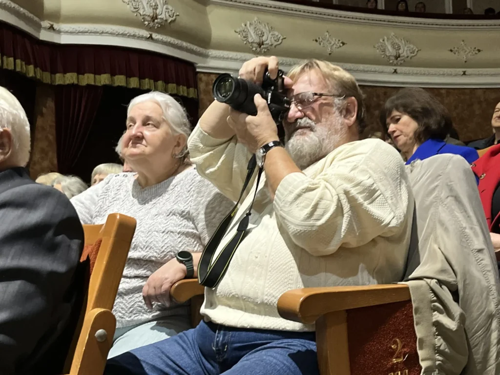 фотограф у залі фотографує оркестр на сцені