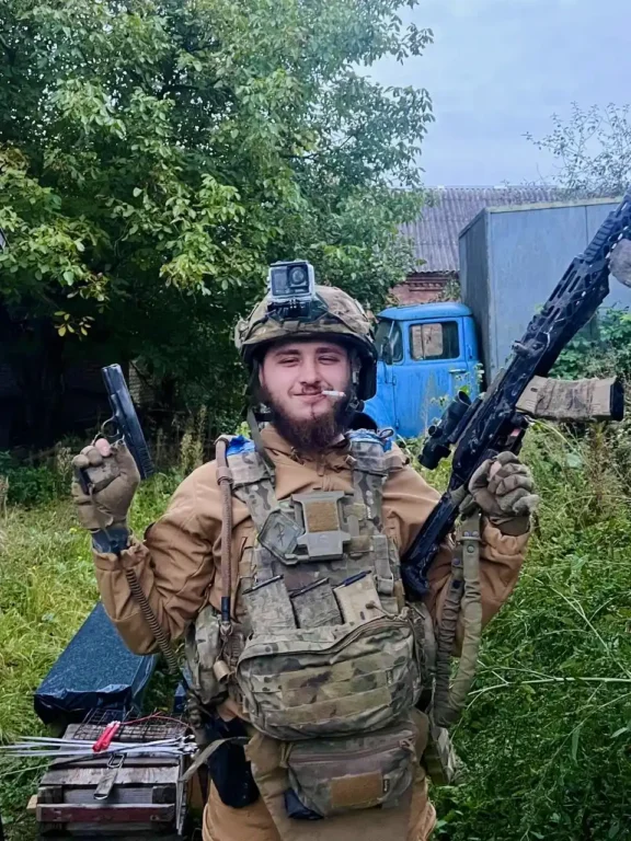 Артем зі зброєю на тлі вантажівки на сільському подвір'ї