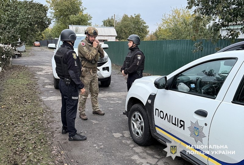 полійцейські поряд із службовими машинами на вулиці в приватному секторі