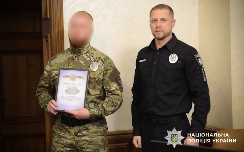 Військовик тримає в руці відзнаку, поряд стоїть поліцейський, який його нагороджував
