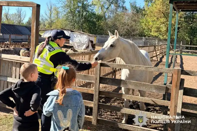 поліцейська з підопічними дітьми в екопарку годує тварин