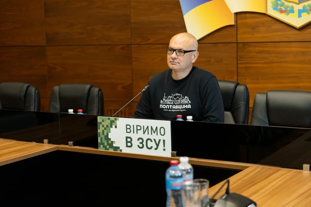 Євген Кончаковський у залі засідань сидить за столом президії