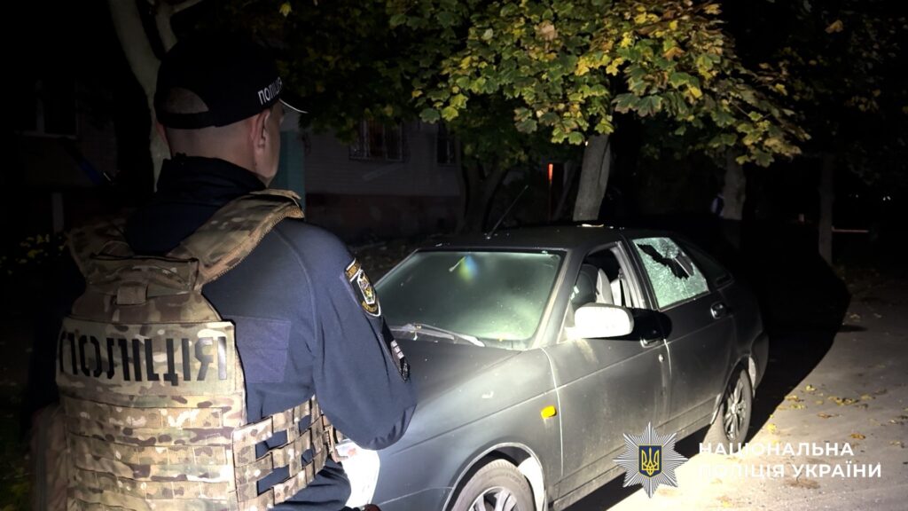 поліцейський у бронежилеті біля легкового авто