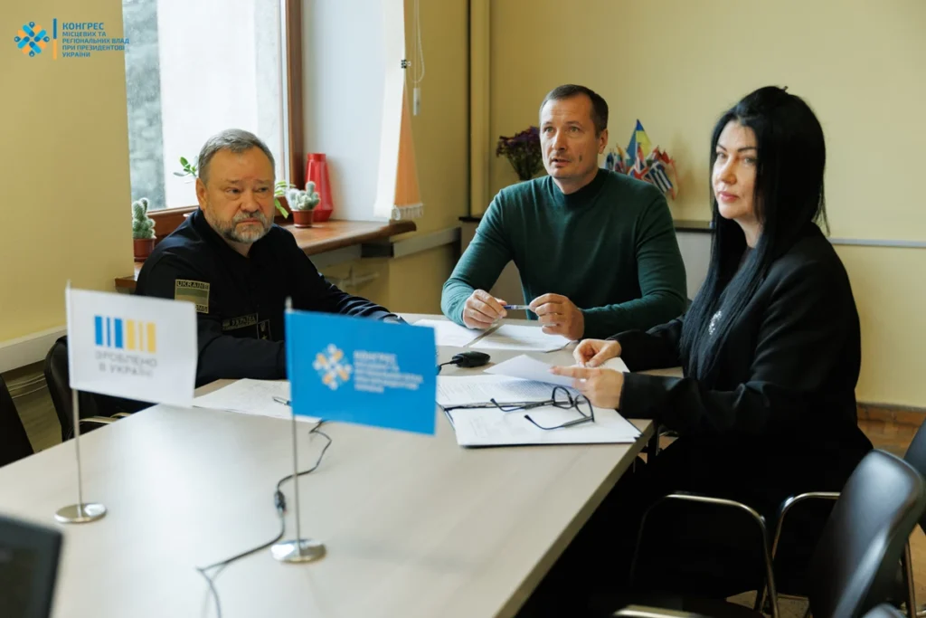 чоловік у формі митника, чоловік у цивільному одязі та жінка сидять за столом у кабінеті